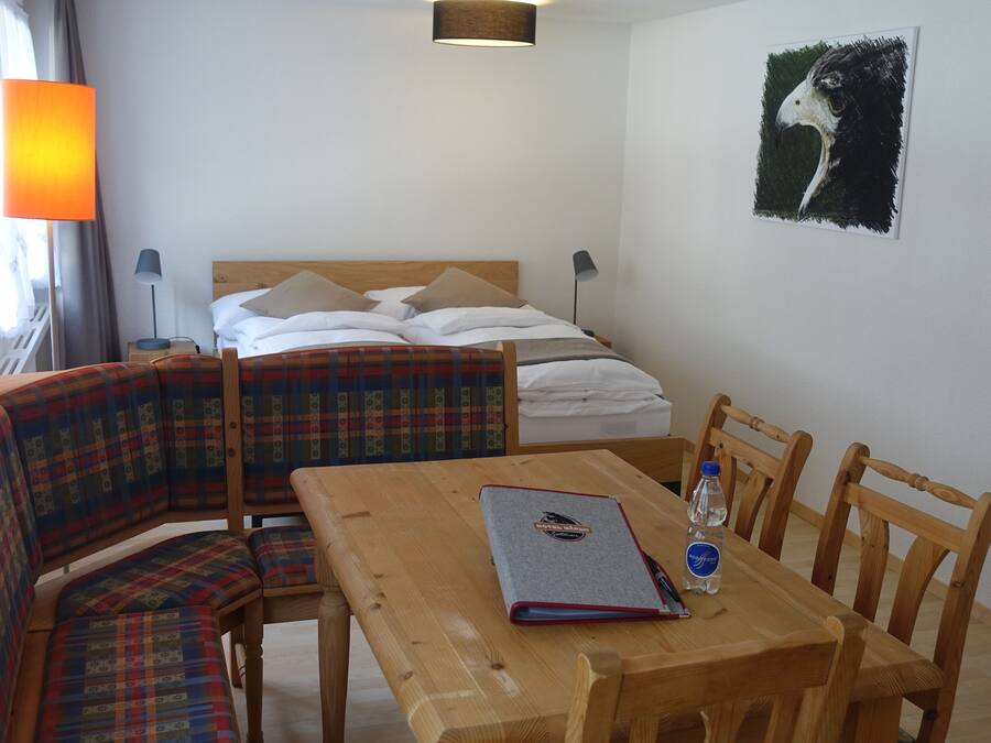 Habitación de hotel con cama, una mesa con sillas, sofá, lámpara y un cuadro en la pared.