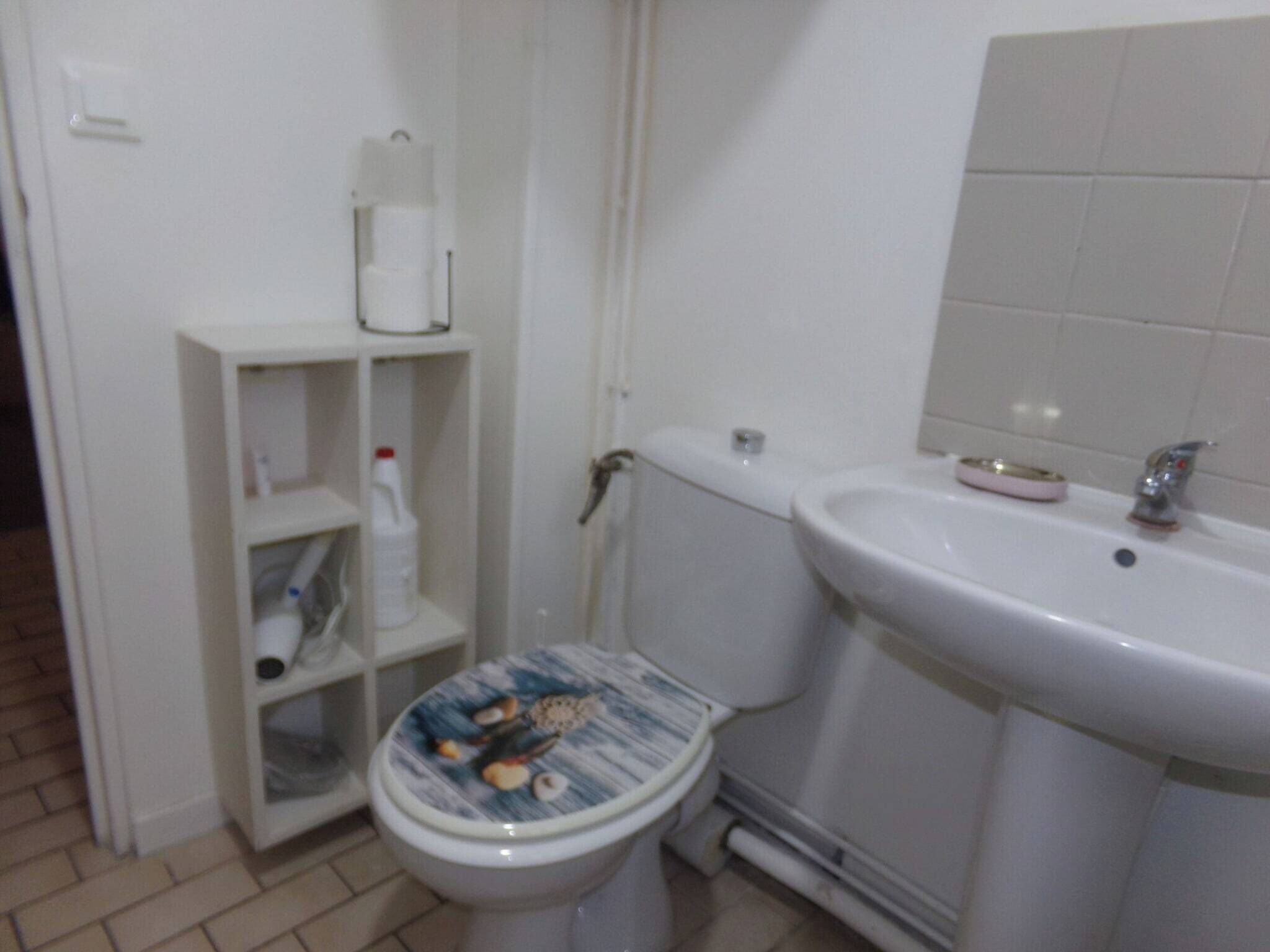Een badkamer met toilet, wastafel en een plank met toiletartikelen.