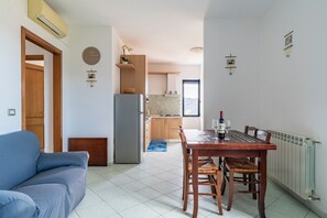 A modern kitchen with a dining area, a sofa, and a clock on the wall.