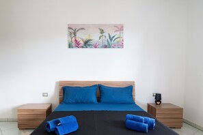 A bedroom with a bed, two nightstands, a painting, and a lamp.
