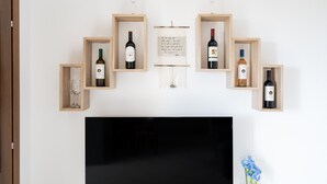 A wall-mounted display of wine bottles in wooden boxes, a framed text, and a black TV screen.