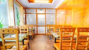 Un restaurant avec des chaises et des tables en bois, un mur recouvert de carreaux et une grande fenêtre.