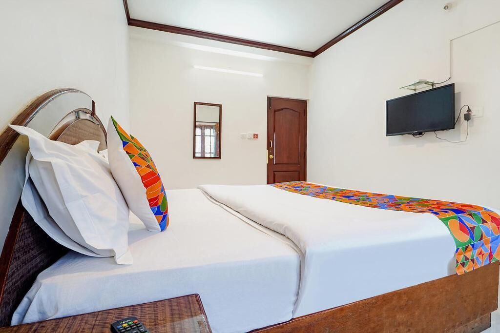 A hotel room with a bed, a television mounted on the wall, and a door.