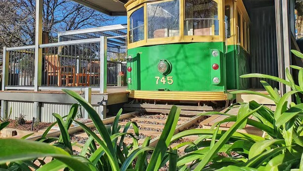 A green and yellow tram with the number 745 parked at a station. - Yarra Valley Tram Stay (Lilydale)