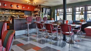 A retro-themed restaurant with a bar area, red chairs, and a checkered floor.