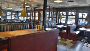 A diner with booths and tables, featuring a checkered floor and pendant lighting.
