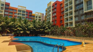 A swimming pool surrounded by palm trees and multi-colored buildings.
