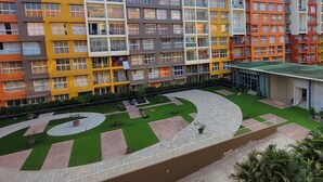A multi-story residential building with balconies and a central courtyard with green lawns and pathways.