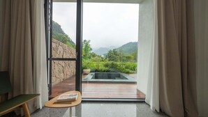 Una habitación con vistas a un paisaje montañoso, un muro de piedra y una terraza de madera con un jacuzzi.