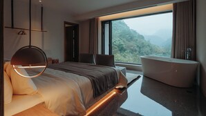 Un dormitorio moderno con una cama grande, una bañera y vistas a un paisaje montañoso.