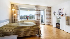 Een slaapkamer met een bed, een raam met gordijnen, een bureau en een kast.