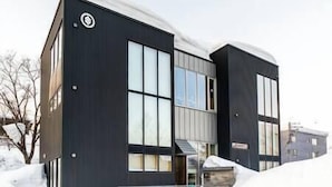 Un bâtiment moderne à deux étages, doté de grandes fenêtres et d’une façade sombre.