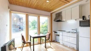 Une cuisine moderne avec des armoires blanches, un plafond en bois et une grande fenêtre offrant une vue sur l’extérieur.