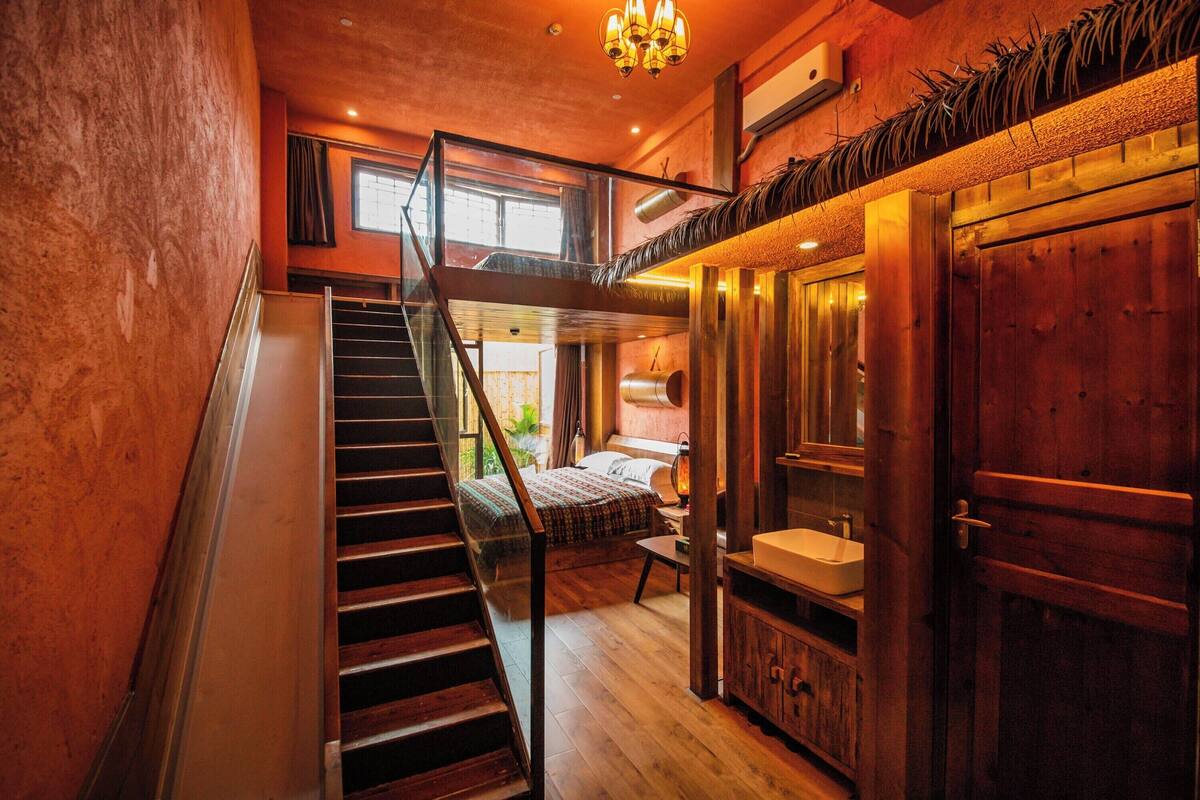 A staircase leading to a bedroom with a bed, a bedside table, and a window.
