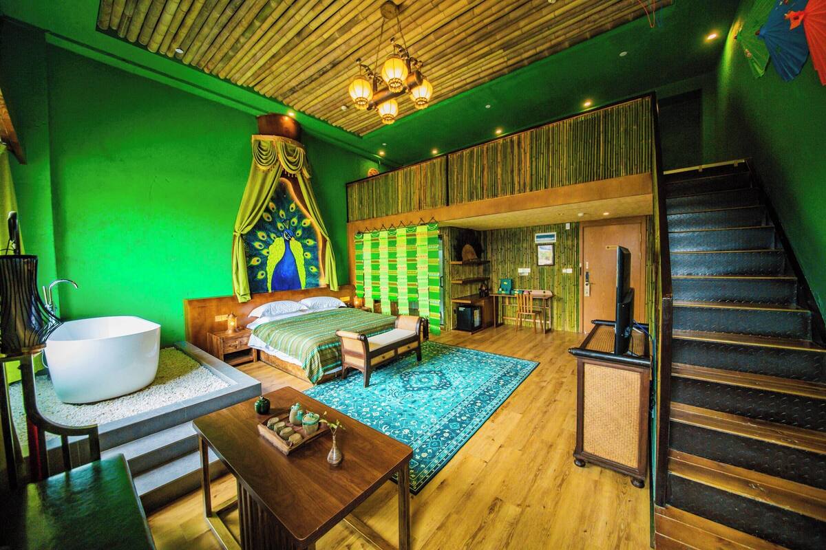 A room with a large bed, a bathtub, a wooden table, and a staircase.