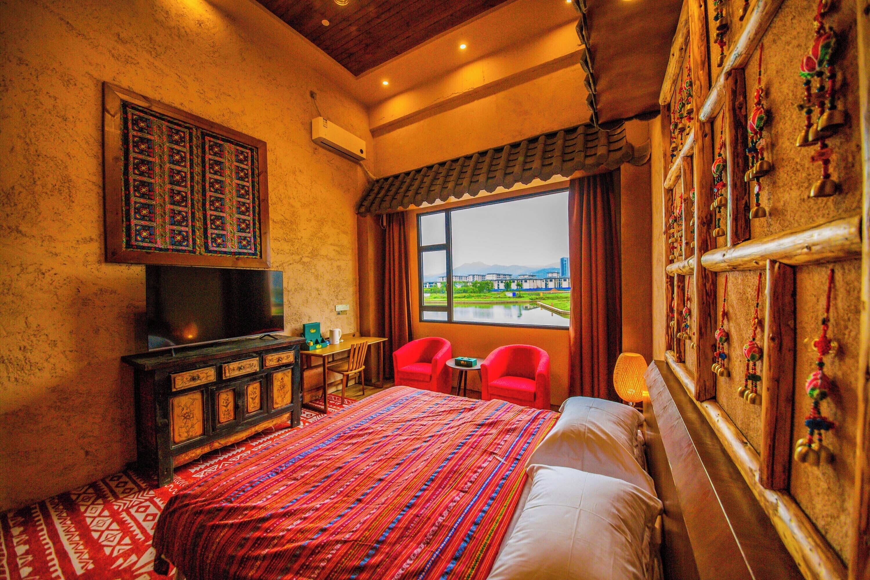 A hotel room with a large bed, a TV, a desk, and a view of a body of water.