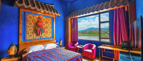A room with a bed, a desk, a chair, and a window with a view of a landscape.