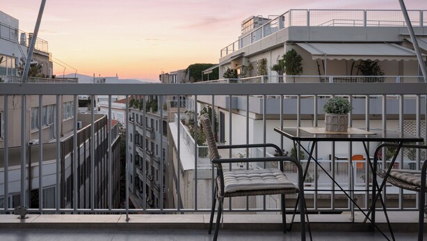 A balcony with a view of adjacent buildings and a sunset. - Acropolis Sandra Deluxe Apartment, Bill & John Apartments & Villas (Athens)
