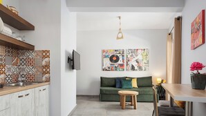 A modern kitchen with a tiled backsplash, a green sofa, and a dining area with a table and chairs. - Acropolis Sandra Deluxe Apartment, Bill & John Apartments & Villas (Athens)