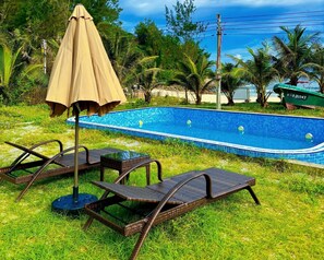 Une piscine avec des chaises longues et un parasol.
