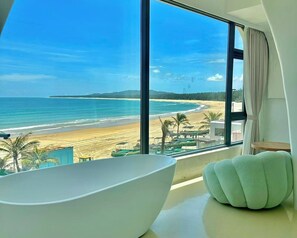 A modern bathroom with a large bathtub and a view of a beach and ocean. - Nirvana Seaview Homestay (Wanning)