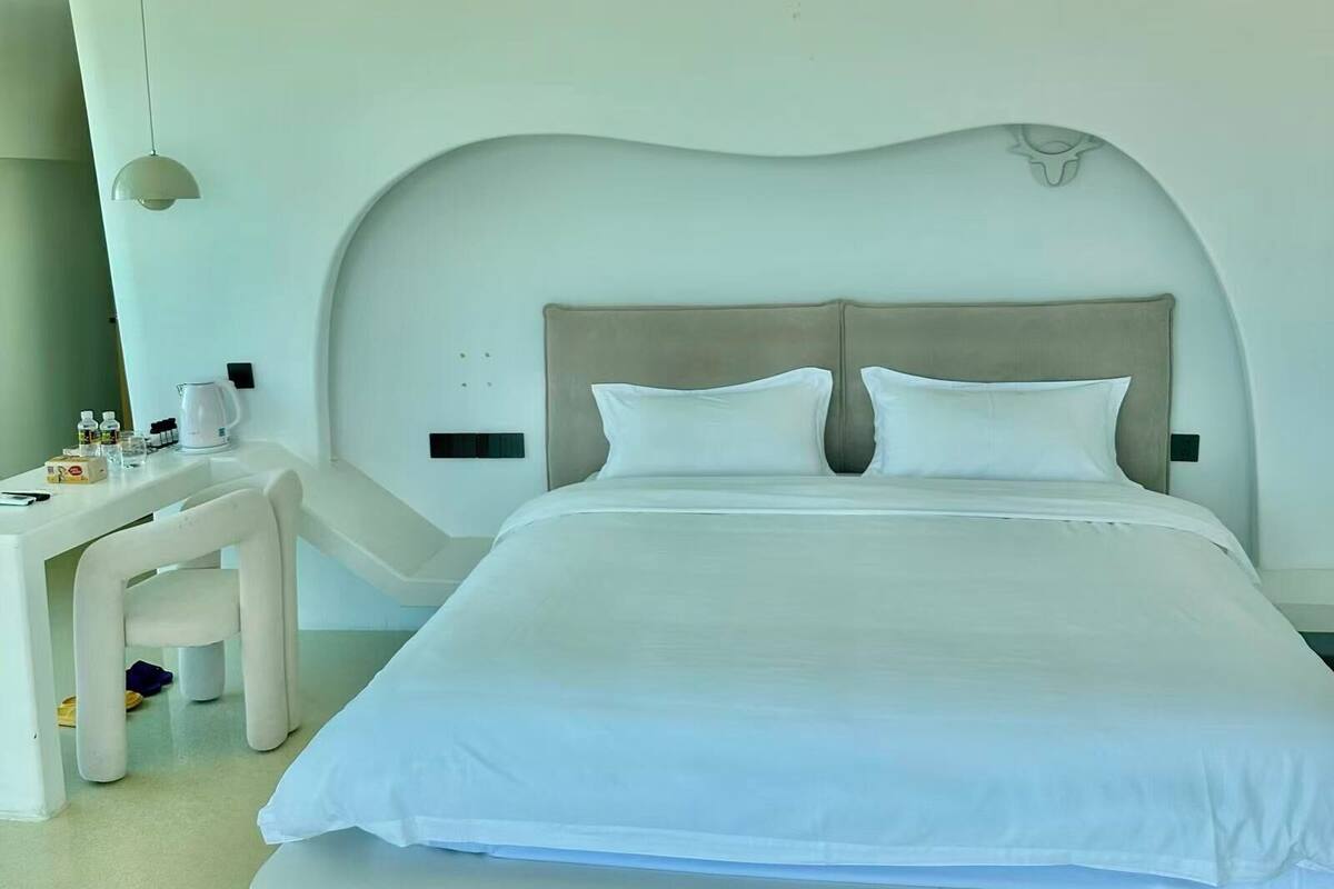 Una habitación de hotel moderna con una cama grande, un escritorio con una silla y una cafetera.