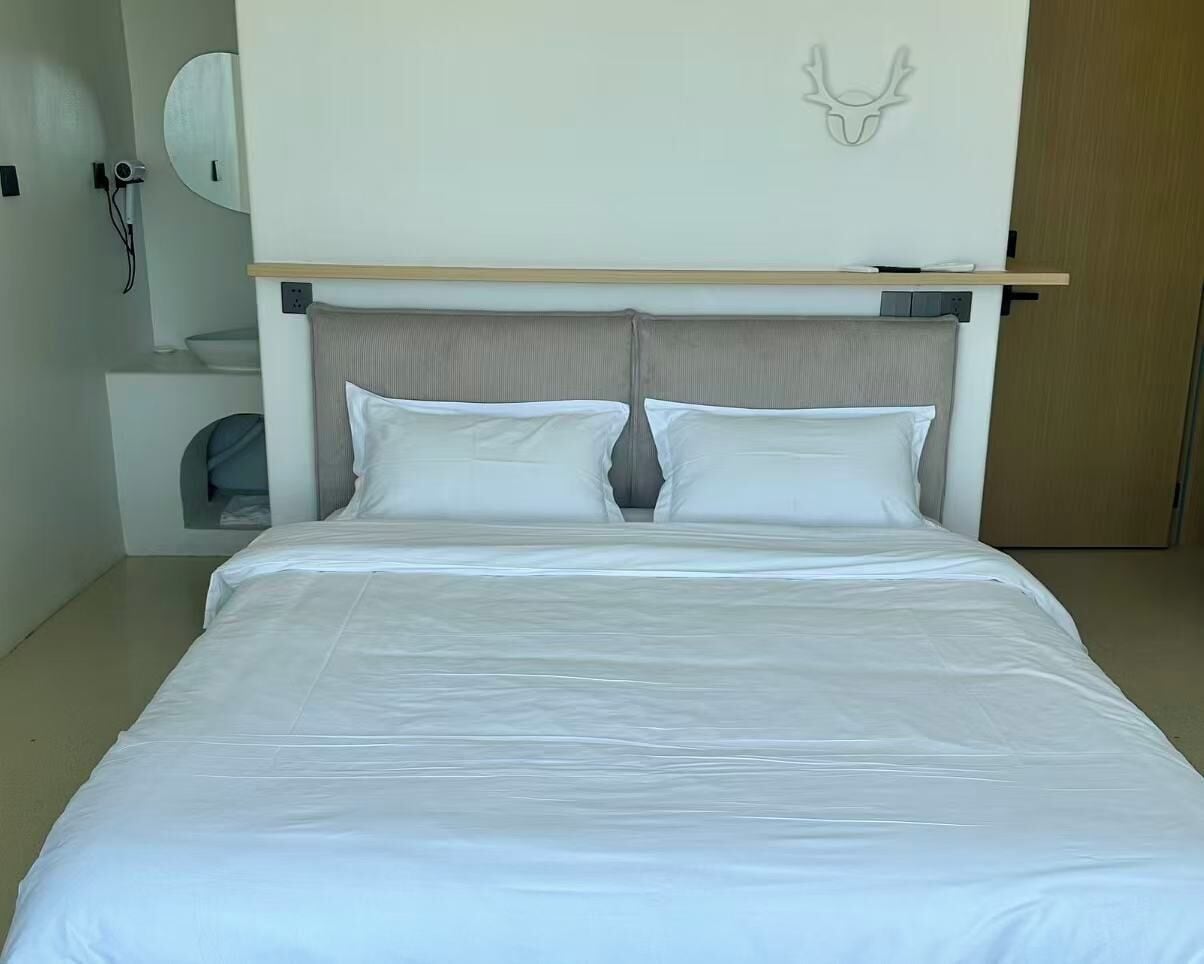 Cama bem arrumada com lençóis brancos em quarto de hotel.