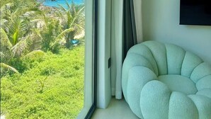 A room with a view of a beach and ocean, a large window with curtains, and a round, light-colored sofa. - Nirvana Seaview Homestay (Wanning)