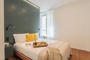 Une chambre à coucher moderne avec un lit, une table de chevet et une fenêtre avec des rideaux.
