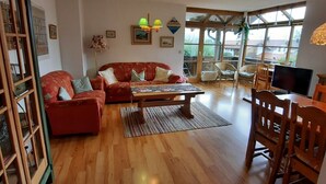 Un salon avec un plancher en bois, un canapé rouge, une table basse et un téléviseur.
