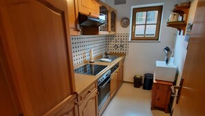 Une cuisine avec des meubles de rangement en bois, une cuisinière, un évier et une fenêtre.
