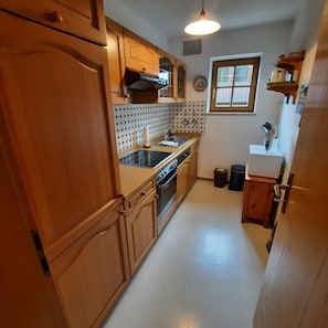 A kitchen with wooden cabinets, a stove, a sink, and a window. - Apartment 'Krämer' with Balcony and Wi-Fi (Burgberg)