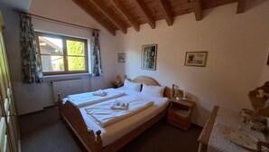 Une chambre à coucher avec un lit en bois, une fenêtre avec des rideaux, une table de chevet et un mur orné de tableaux.