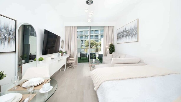 Ein modernes Hotelzimmer mit einem Bett, einem Schreibtisch mit Stuhl, einem Fernseher und einer Essecke mit Glastisch.