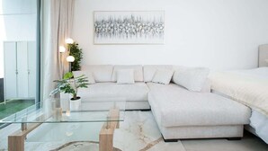 Ein modernes Wohnzimmer mit einem Glastisch, einem beigefarbenen Sofa und einem Gemälde an der Wand.