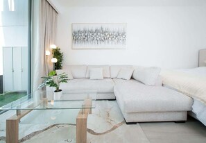 Un soggiorno moderno con un tavolino in vetro, un divano color beige e un quadro appeso al muro.