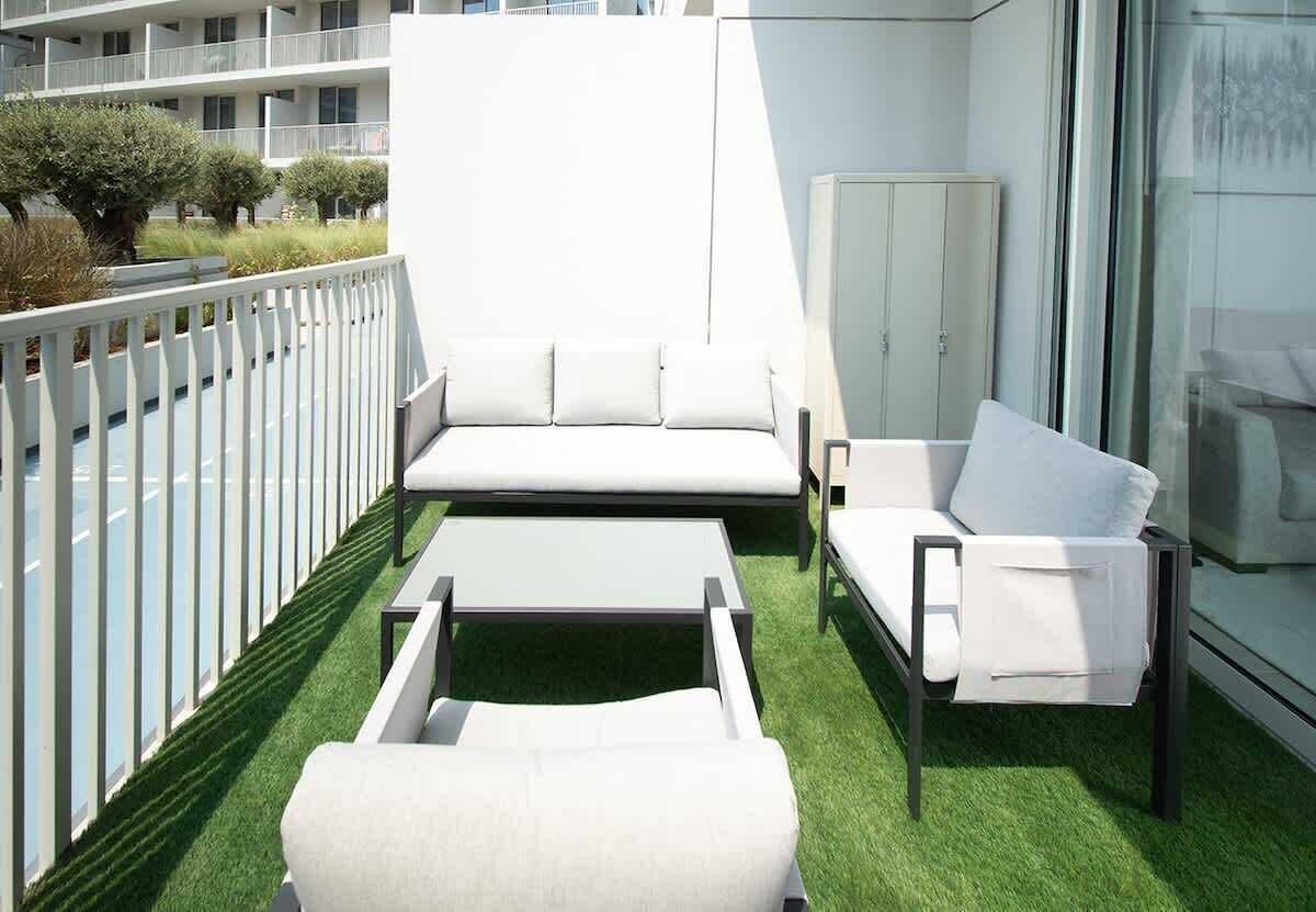 A balcony with a white sofa, a white armchair, and a small table.
