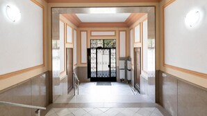 A corridor with a polished floor, a black gate at the end, and a light fixture on the wall. - Stunning views over iconic Sagrada Familia! Building perfect for large groups! (Barcelona)