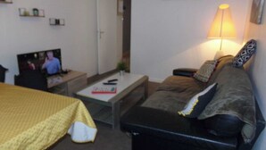 En stue med sofa, sofabord, fjernsyn og lampe.