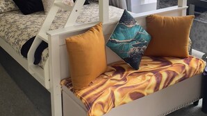 Een kamer met stapelbedden, een slaapbank en een groot raam met gordijnen.