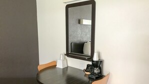 A small, dark wooden table with two orange chairs, a white tissue dispenser, and a coffee maker.
