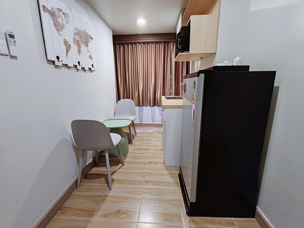 A compact kitchen with a refrigerator, a small table, two chairs, and a world map on the wall.