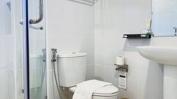 Un baño con cabina de ducha de vidrio, inodoro y lavabo.