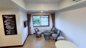 A modern living room with a sofa set, a coffee table, and a TV mounted on the wall. - Harmony Chiang Mai Old Town (Chiang Mai)