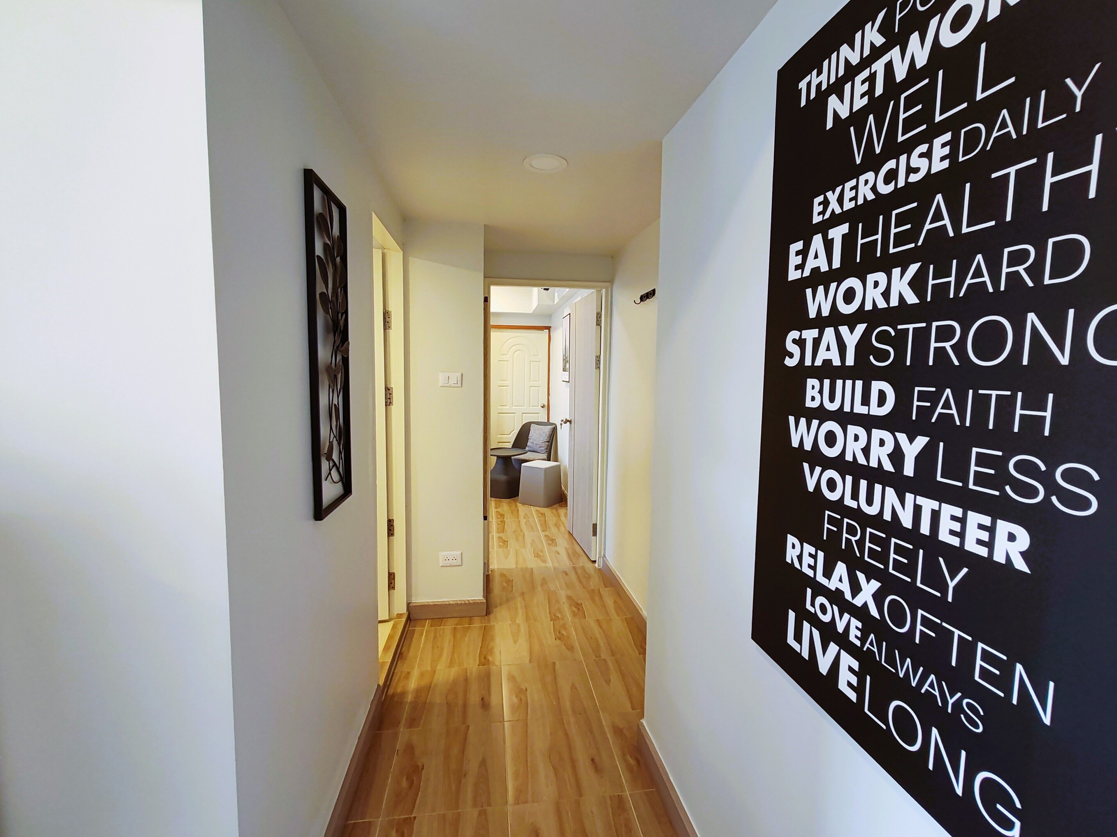 A hallway with a motivational poster on the wall and a wooden floor.