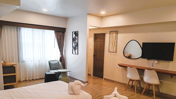 A hotel room with two beds, a desk, a chair, a TV, and a door. - Harmony Chiang Mai Old Town (Chiang Mai)