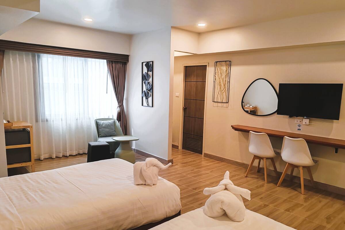Ein Hotelzimmer mit zwei Betten, einem Schreibtisch, einem Stuhl, einem Fernseher und einer Tür.