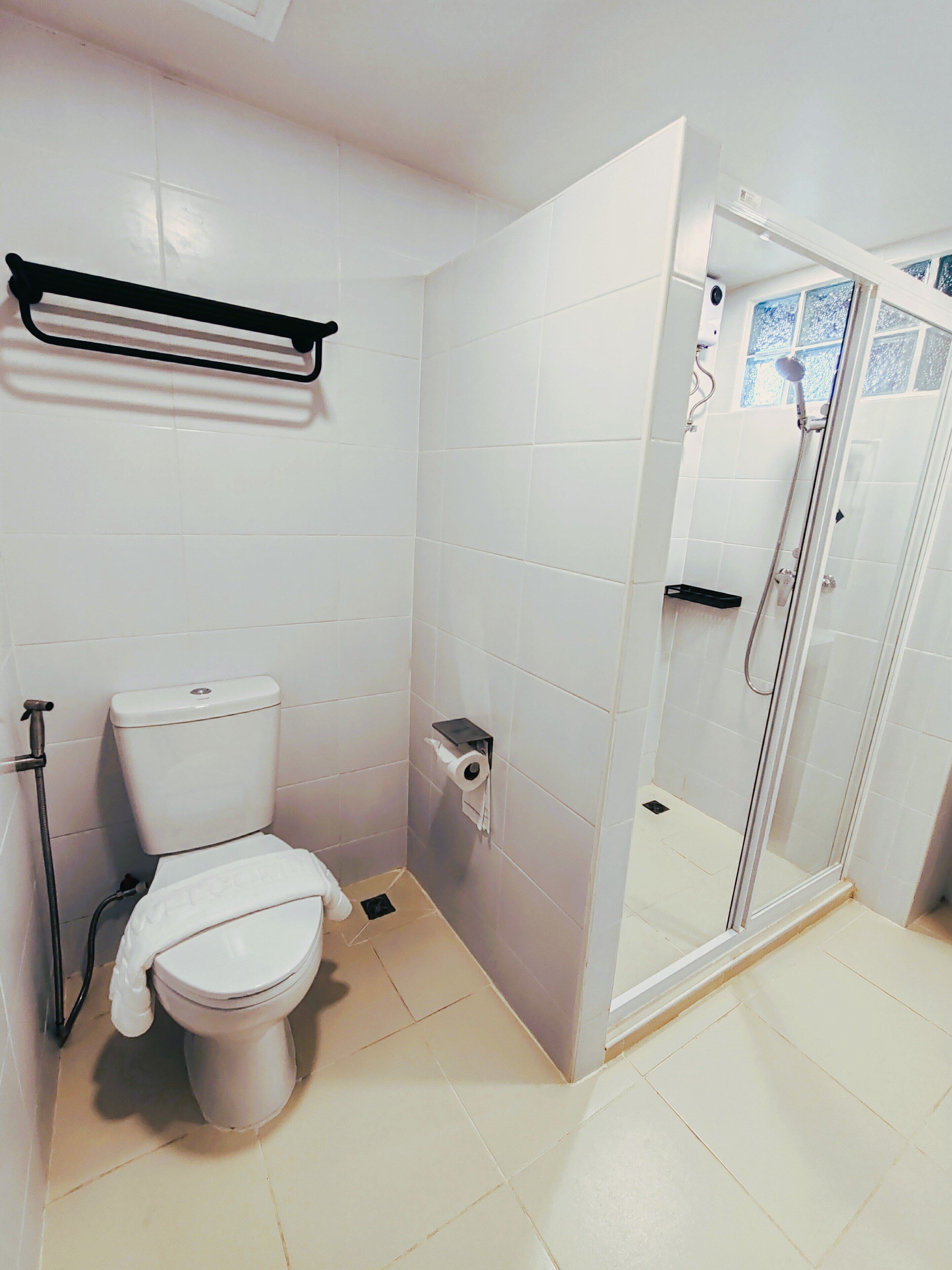 Un baño con inodoro, cabina de ducha y toallero.