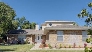 A two-story house with a brick facade, a front porch, and a well-maintained lawn. - Classy Comfy 3-bedroom house with AC in Palm Bay (Palm Bay)