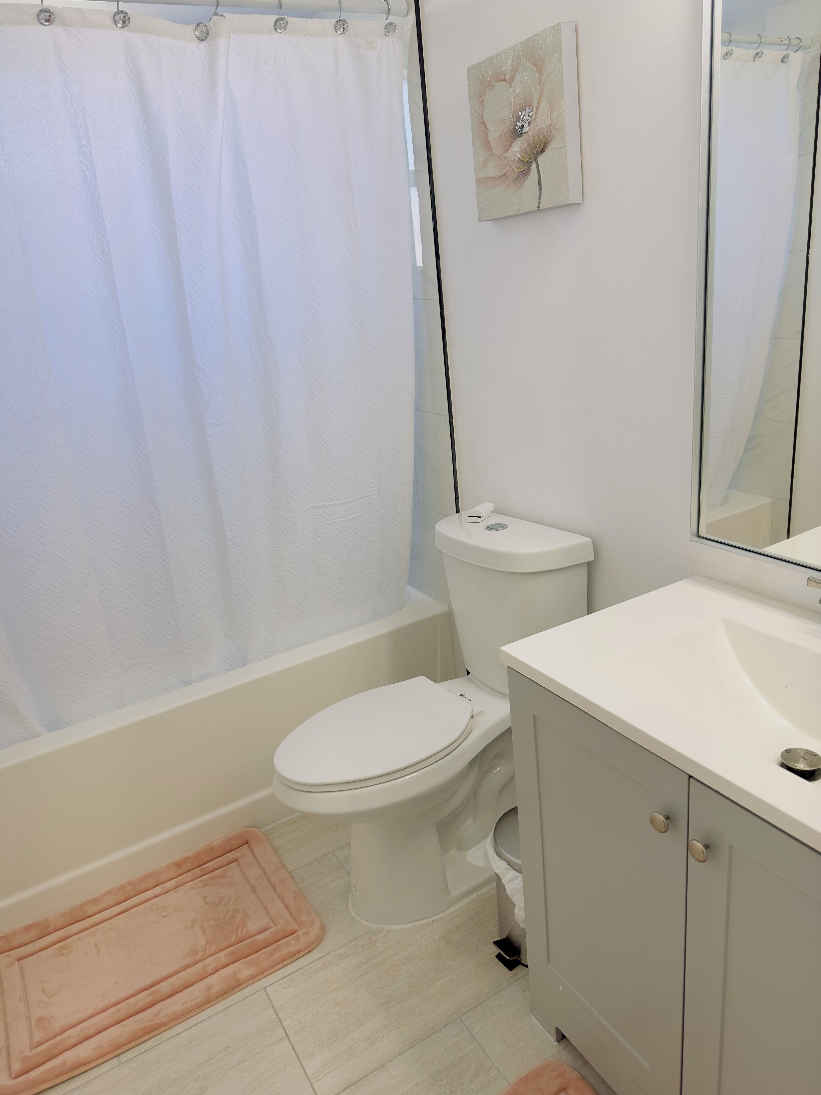 Un baño con inodoro, lavamanos, espejo y cortina de ducha.